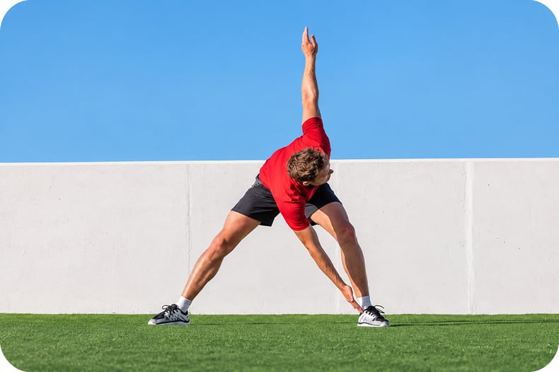 A man in a red shirt holding his right arm back and touching his left hand to his right foot for his sports physical therapy exercise 