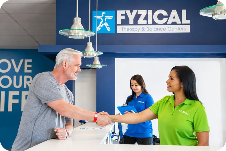 A FYZICAL team member greeting a patient at the front desk of a FYZICAL Therapy & Balance Center., a top 5 medical franchises in the U.S.