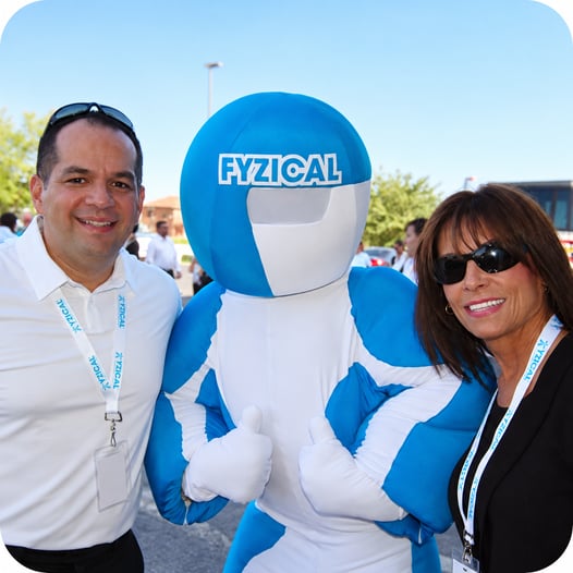 Risa Hofmeister and Mike posing with the FYZICAL mascot at an outdoor FYZICAL event.