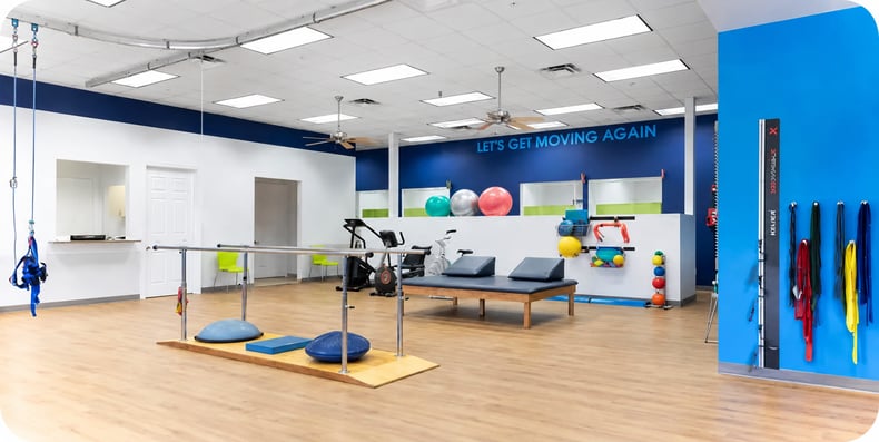 FYZICAL physical therapy clinic interior featuring balance training equipment, therapy tables, and rehabilitation exercise space.