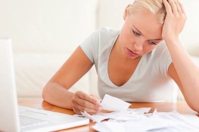 a woman looking stressed as she looks at bills