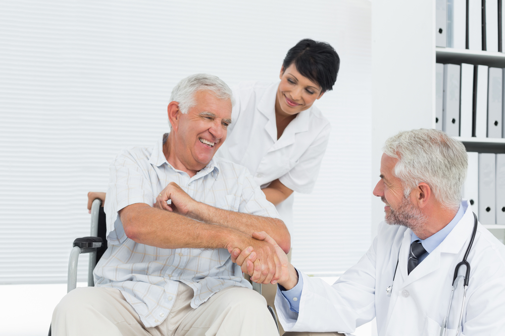 Happy senior patient and doctor shaking hands in the medical office
