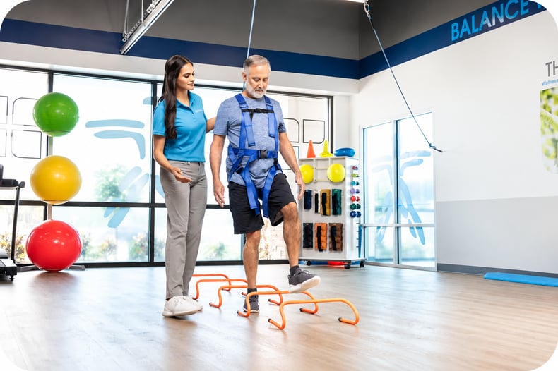 FYZICAL physical therapist assisting a patient with balance training exercises using rehabilitation equipment.