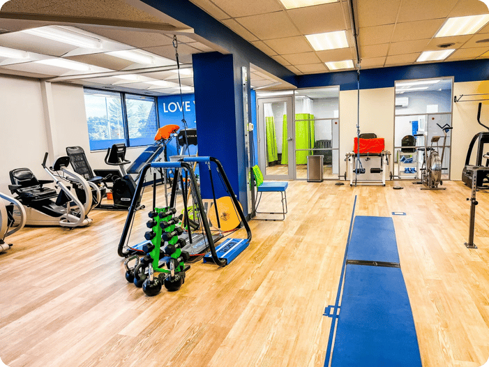 FYZICAL physical therapy clinic interior with rehabilitation equipment, exercise machines, weights, and treatment areas.