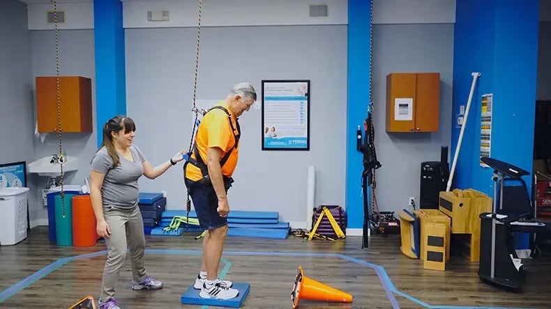 elderly patient standing on small platform rehabbing