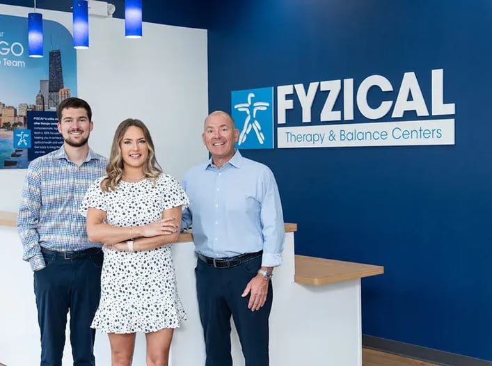 Three franchisees standing in front of Fyzical check in counter