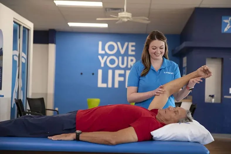 therapist stretching patient's shoulder overhead