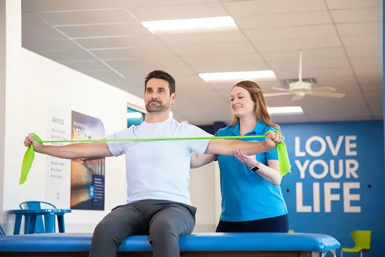 physical therapist helping patient stretch shoulders