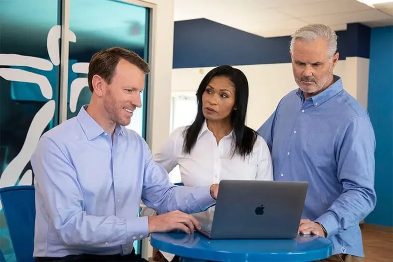 three people looking at a laptop screen