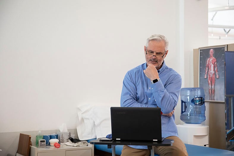 elderly man looking intently at a laptop