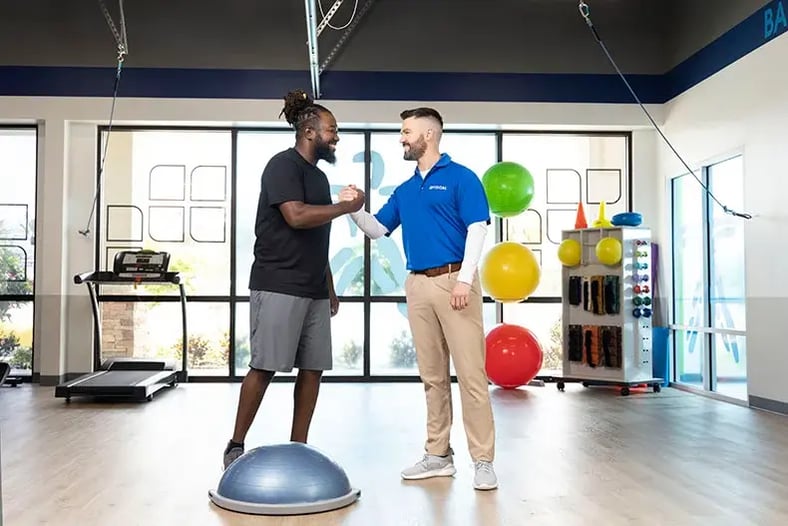 Therapist and patient shaking hands in workout room