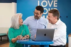 one woman and two men discussing business in front of a computer