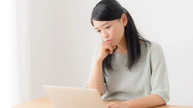 woman looking sad as she looks at her laptop