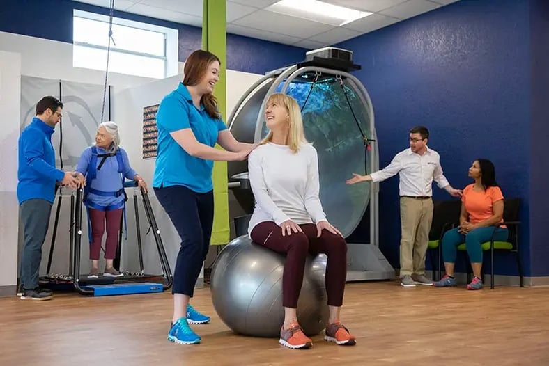 Physical Therapists working with patient on exercise ball